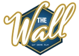 Hexagonal logo with the text "THE Wall" in gold cursive on a blue background, accompanied by the mention "Live Game Show"
