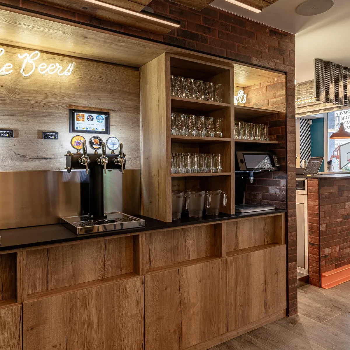 Eine Bierbar mit mehreren Zapfhähnen, Regalen für Gläser und Bildschirmen, die Informationen anzeigen, in einem modernen Innenraum mit Holzelementen und Ziegeln
