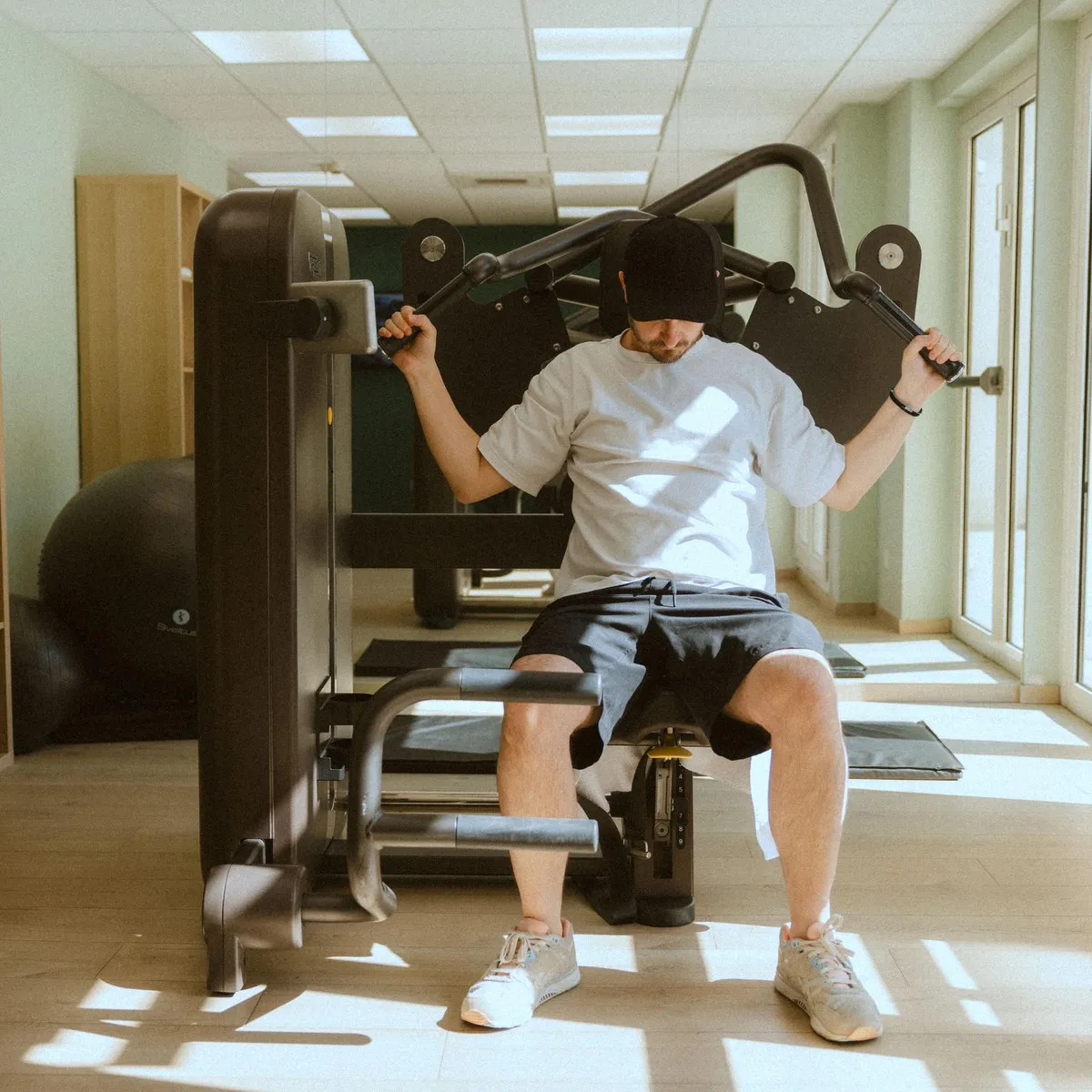 Ein Mann nutzt ein Trainingsgerät in einem gut beleuchteten Fitnessstudio.