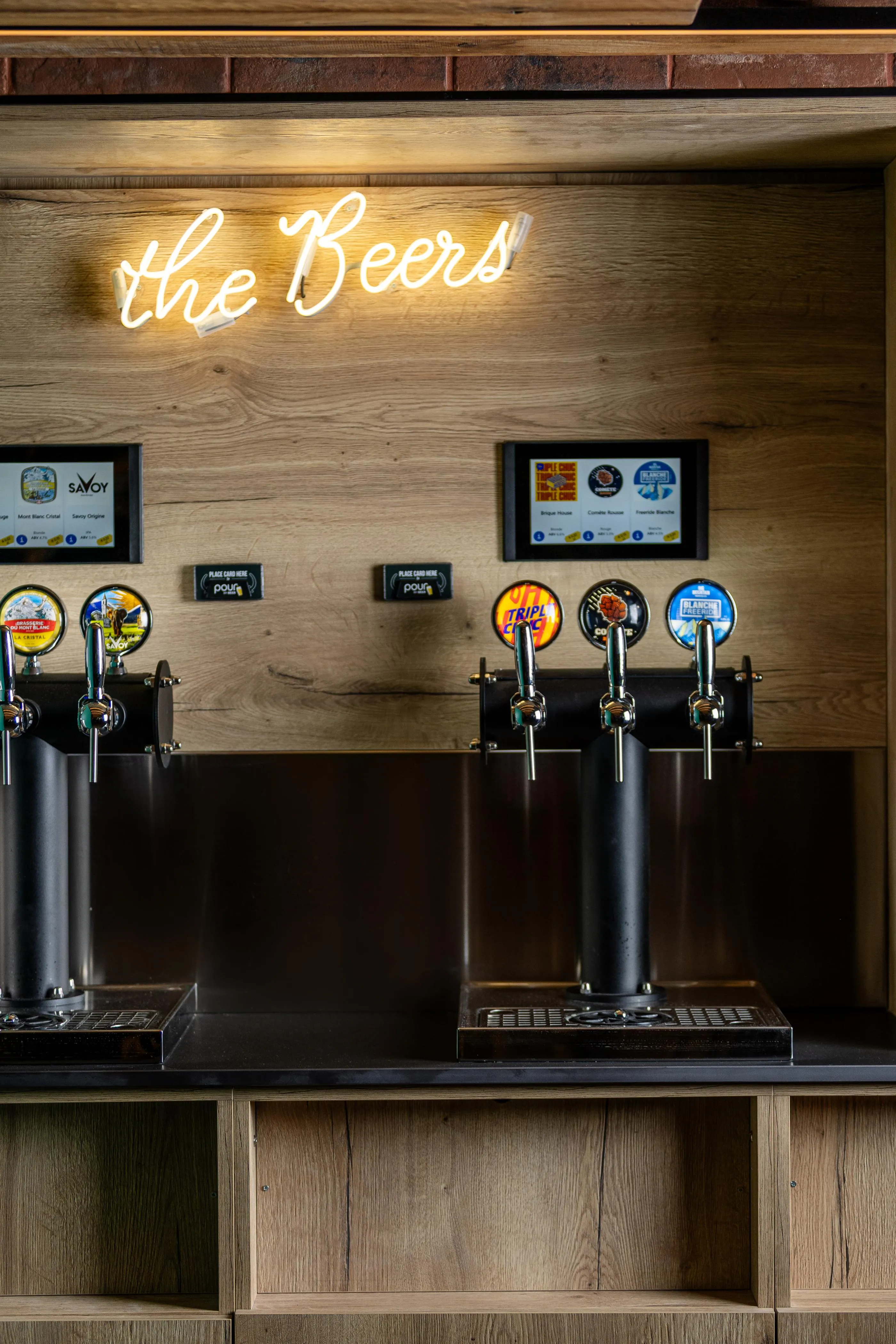 Un mur en bois avec des robinets à bière et une enseigne lumineuse "the Beers"