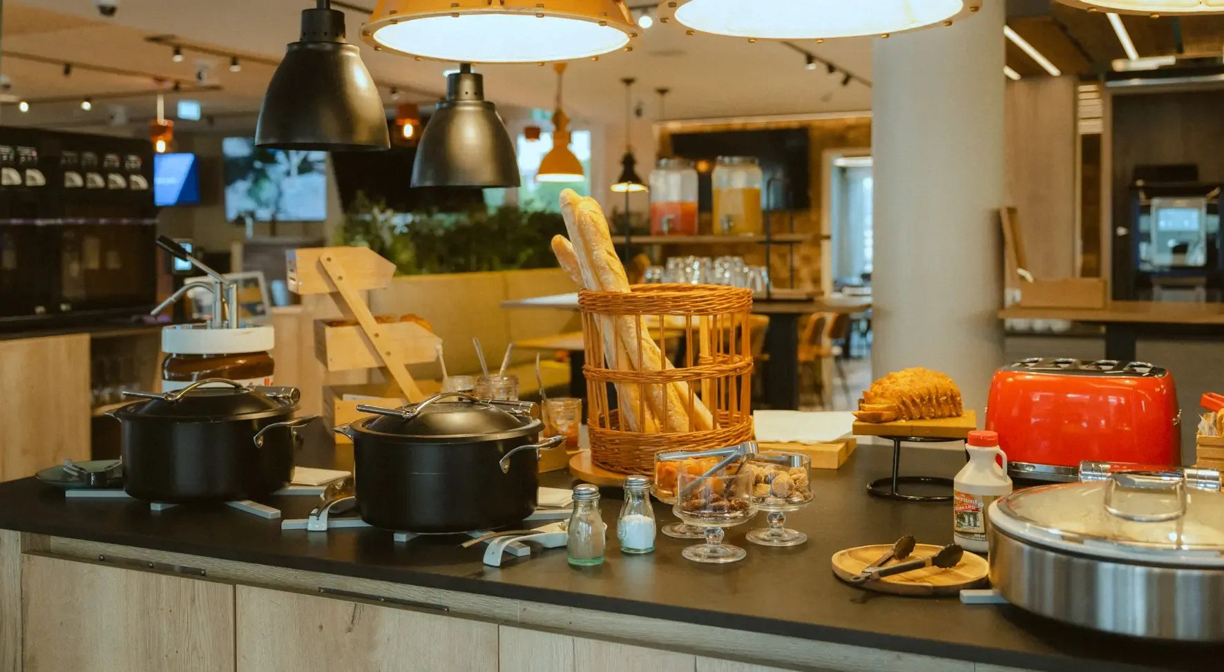 A restaurant buffet with serving dishes, chopsticks in a basket, food platters, and drinks available.