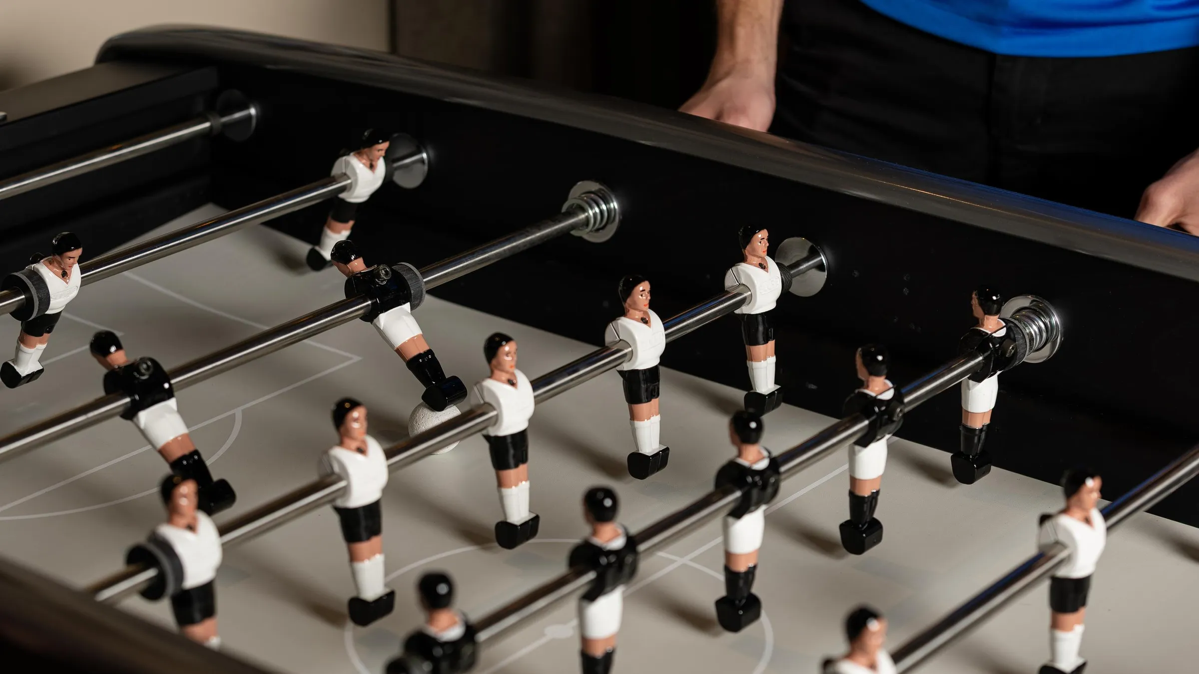 Table de baby-foot avec des figurines de joueurs en plastique positionnées sur les barres métalliques
