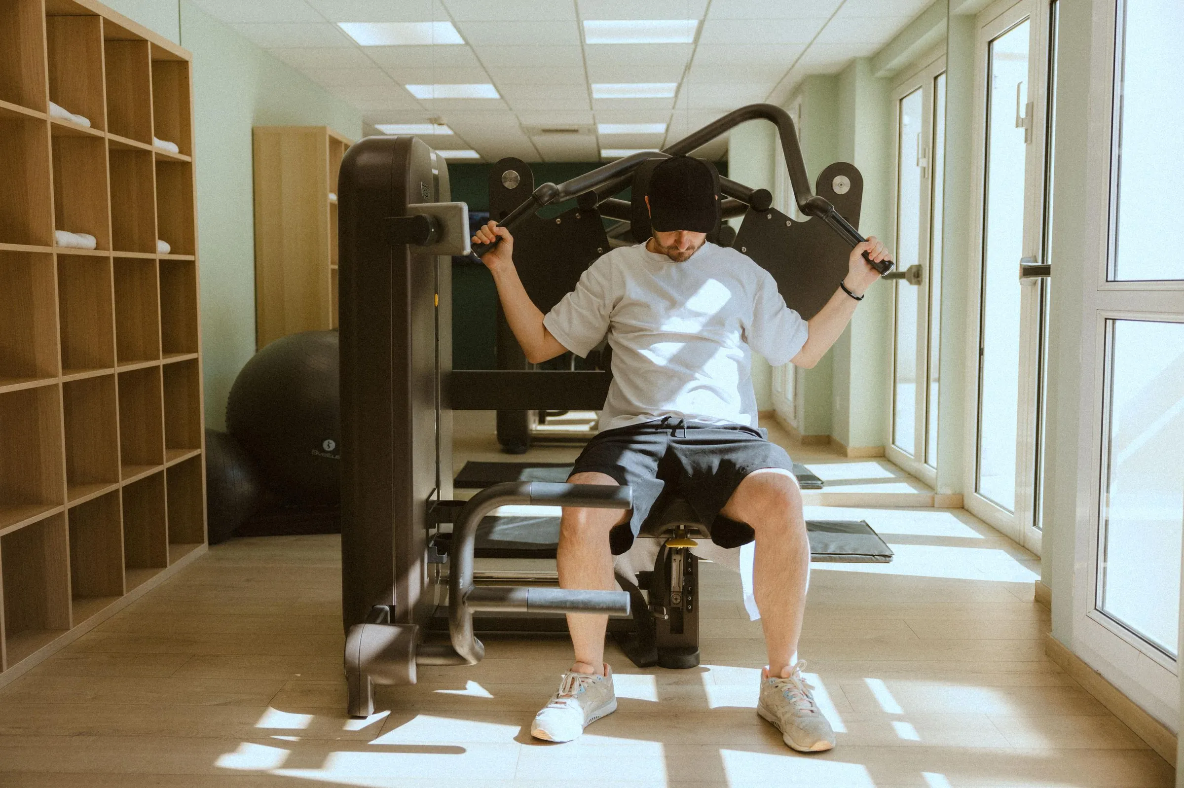 A man uses a weight machine in a well-lit gym.